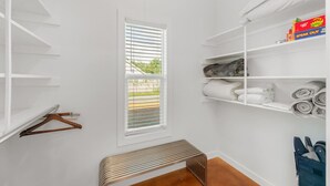 Un placard blanc avec des étagères, un banc et une fenêtre équipée de stores.