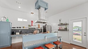 Une cuisine moderne dotée d’un îlot central, de tabourets de bar et d’une grande fenêtre.