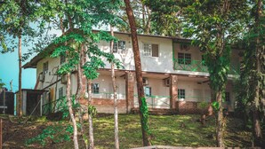 A two-story building with a brick facade, multiple windows, and a green railing on the upper level. - Hotel La Ceiba Panamá  (San José del General)
