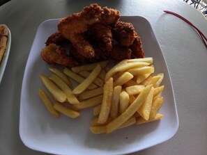 Ein weißer Teller mit gebratenem Hähnchen und Pommes Frites.