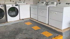 A laundry room with four white washing machines and a large industrial washing machine. - Hotel La Ceiba Panamá  (San José del General)