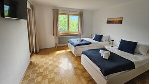 Habitación de hotel con dos camas, televisión, ventana con cortinas y radiador.
