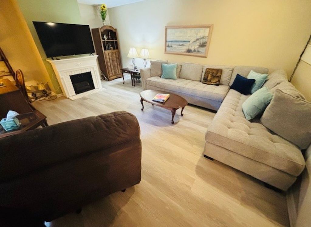 A living room with a fireplace, a television, a sofa, a coffee table, and a lamp.
