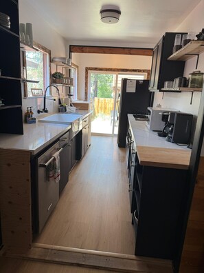 Cozinha moderna com ilha central, eletrodomésticos embutidos e vista para o exterior.