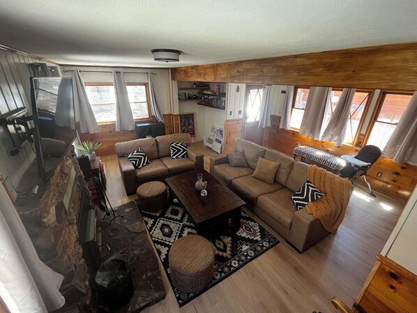 A cozy living room with a sofa set, a coffee table, and a rug. There is a television and a wooden cabinet in the room.