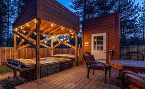 A wooden cabin with a hot tub and deck seating.