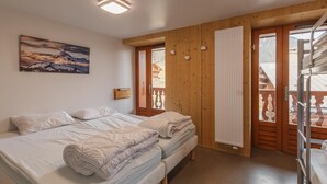 Een slaapkamer met een bed, een schilderij, een raam met uitzicht en een houten deur.