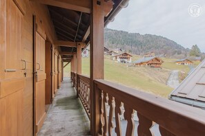 Un couloir en bois donnant sur un village perché sur une colline.