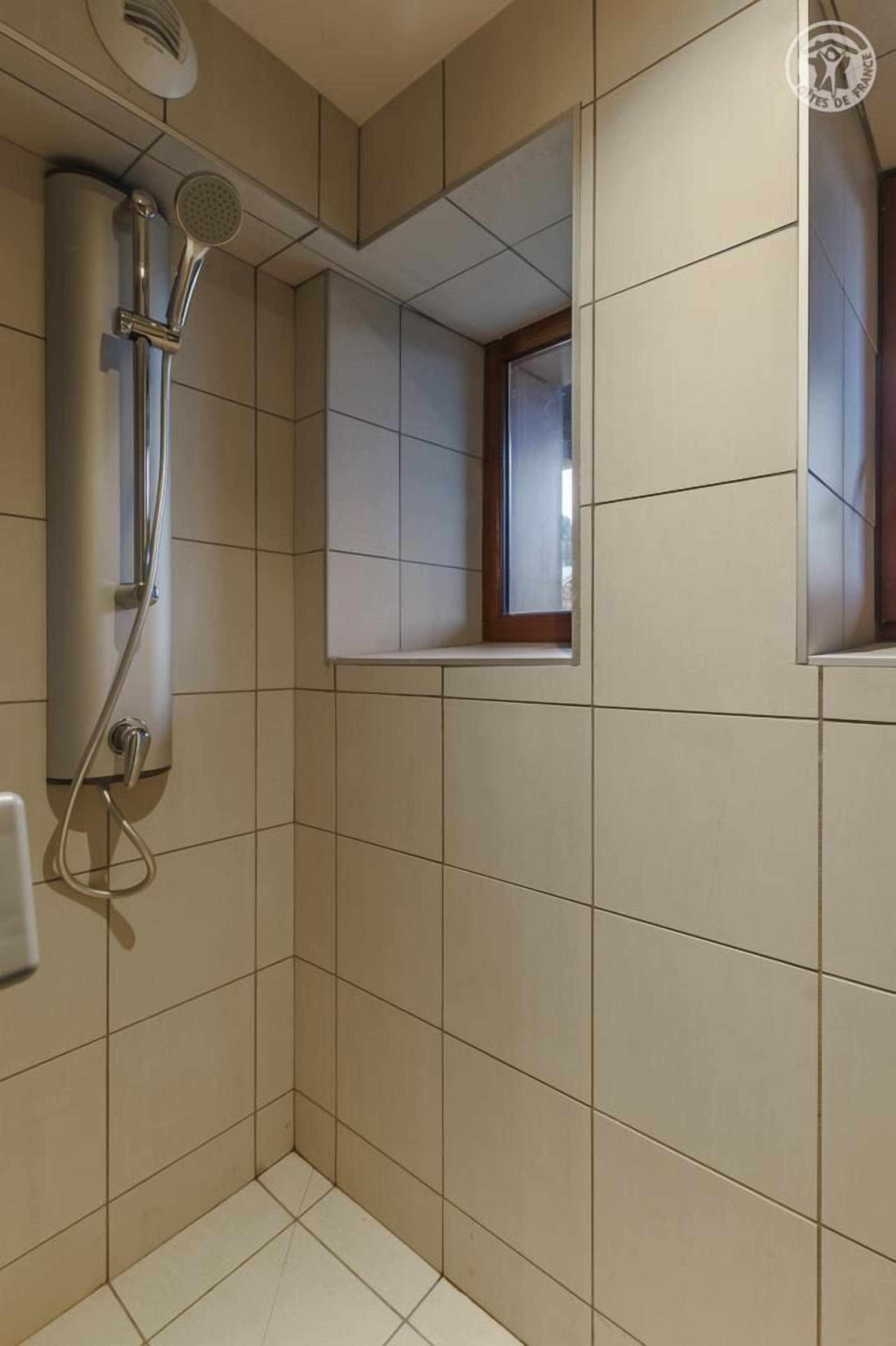 A bathroom with a shower, tiled walls, and a small window.