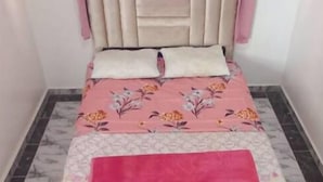 A bedroom with a bed, pink curtains, a headboard, and a floral bedspread. - Tranquil Rooms in Agadir (Agadir)