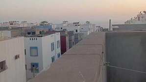 A row of buildings with flat roofs, some with satellite dishes, and a clear sky in the background. - Tranquil Rooms in Agadir (Agadir)