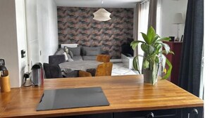 Eine moderne Küche mit Holzarbeitsplatte, schwarzen Schränken und einem Essbereich mit grauem Sofa und einem Wandbild mit Muster.