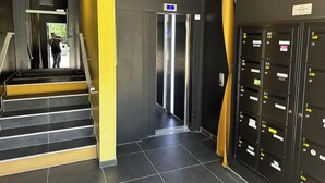 Ein moderner Aufzug, eine Treppe und eine Reihe von Schließfächern in einem Flur.