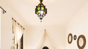 A bedroom with a bed, bedside tables, a hanging light fixture, and decorative wall mirrors. - Suite in the heart of Marrakech's medina (Marrakech)
