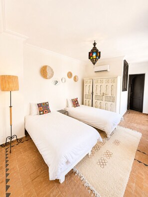 Une chambre avec deux lits, une lampe, des éléments décoratifs sur les murs et un luminaire suspendu.