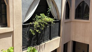 A building with arched windows, a balcony with a plant, and a visible interior space with a bed. - Suite in the heart of Marrakech's medina (Marrakech)