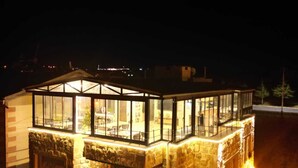 A stone building with a glass upper level and a balcony. - Cappadocia Fiesta Stone House (Nevsehir)