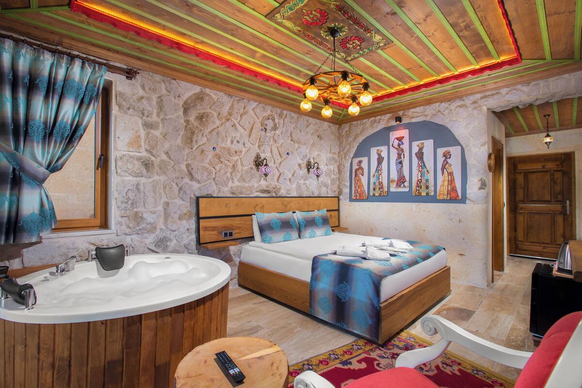 A bedroom with a stone wall, wooden ceiling, and a bed with a blue patterned bedspread.