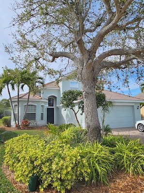 A single-story house with a large tree in front, a garage, and well-maintained landscaping.
