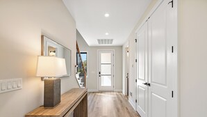 A hallway with a wooden bench, a lamp, and white doors. - Manse Island: Sizzle by the River – Hot Tub, Fire Pit, and Summer Fun (Harrison Township)
