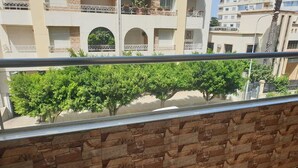 A balcony with a stone wall and a view of a building with multiple balconies and trees. - Super City Center Apartment with Parking  (Tanger)
