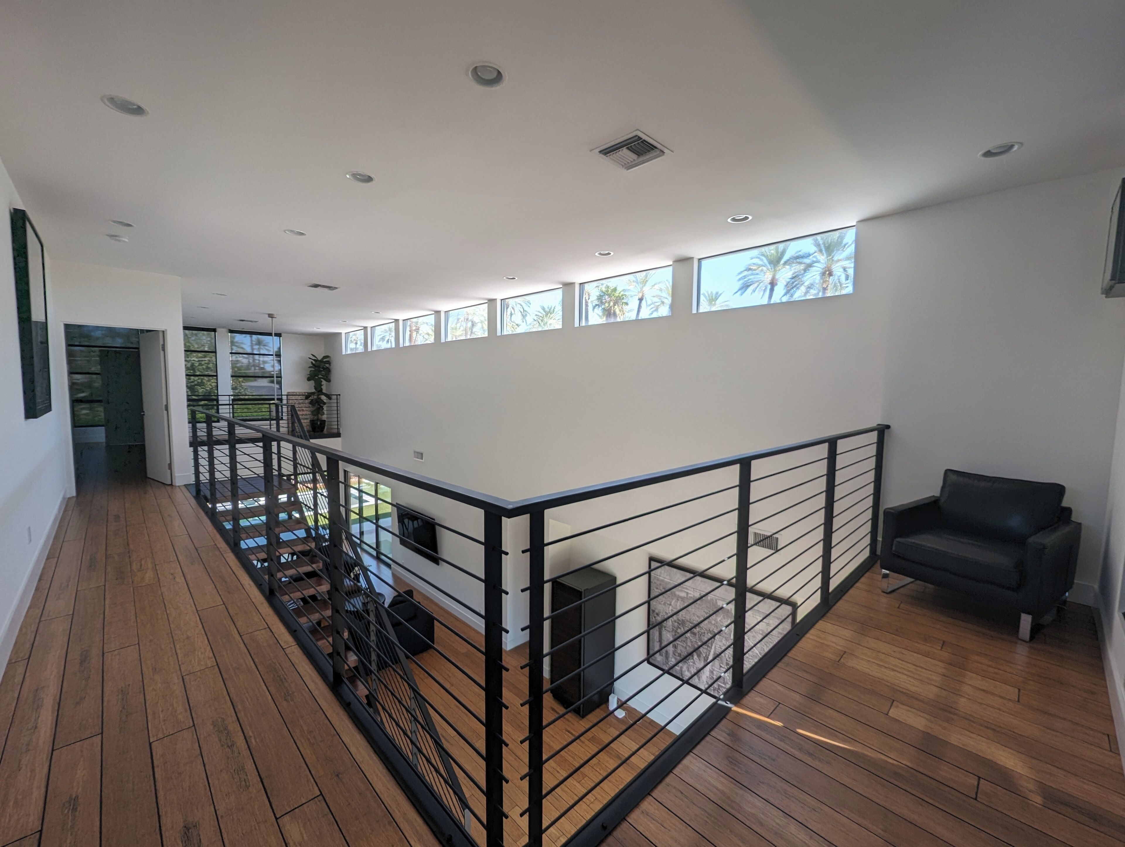 A spacious interior with a wooden floor, a black railing, and a black sofa.
