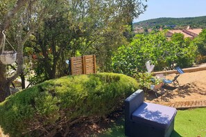Un jardín cuidado con varios árboles, una valla de madera y mobiliario exterior.