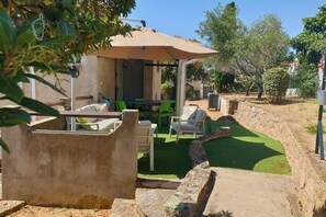 Un espace extérieur aménagé en terrasse, avec un coin salon abrité, une table et des chaises.