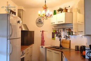Eine Küche mit Kühlschrank, Backofen, Mikrowelle und einer abgehängten Pfannendock.