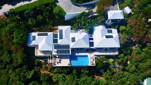 An aerial view of a modern house with a swimming pool, surrounded by lush greenery. - Luxurious Villa w/ Stunning Ocean Views & Pool (St. Thomas)