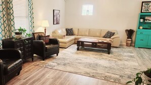 Een woonkamer met een bank, twee fauteuils, een salontafel, een lamp en een plant.
