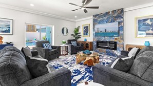 A modern living room with grey sofas, a glass coffee table, and a large TV screen. - Upscale New Build with Private Pool, Steps to the Beach (South Padre Island)