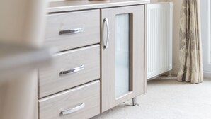 Un baño moderno con un mueble de color claro, un espejo y un radiador.