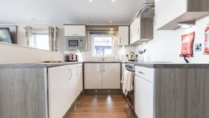 Una cocina moderna con armarios blancos, microondas y pileta.