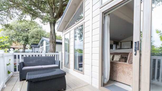 Un espacio al aire libre cubierto con un sofá de mimbre y un ventanal corredero que da a una habitación con un banco acolchado.