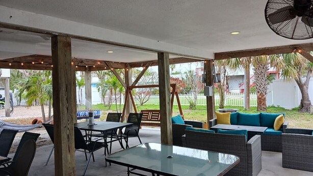An outdoor patio area with tables and chairs, a swing set, and a fan.
