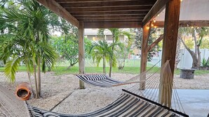 Two hammocks under a wooden pergola with a gravel ground, surrounded by palm trees and a white fence. - El Palmar Unit 2 Third Level from Beach (Indian Rocks Beach)