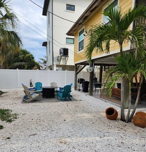 Une terrasse avec des meubles d’extérieur, un barbecue et une clôture blanche.