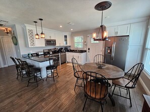 Una cocina moderna con una isla central, armarios blancos y un refrigerador de acero inoxidable.
