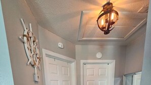 A hallway with wooden flooring, white doors, and a ceiling light fixture. - El Palmar Unit 2 Third Level from Beach (Indian Rocks Beach)