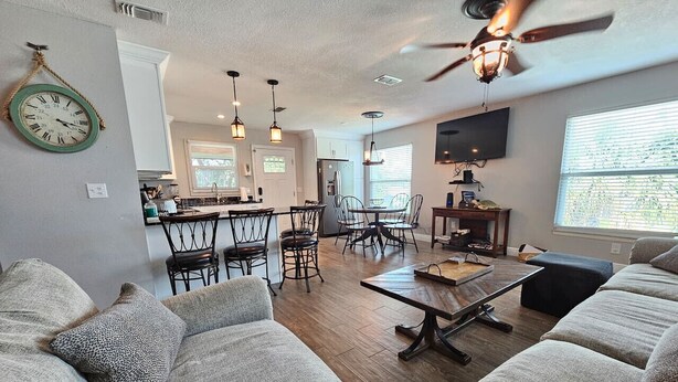 A spacious living room with a large sofa set, a dining area with chairs and a table, and a kitchen in the background. - El Palmar Unit 2 Third Level from Beach (Indian Rocks Beach)