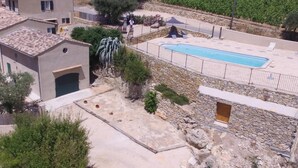 Ett bostadsområde med en swimmingpool, stenmurar och en liten byggnad med ett garage.