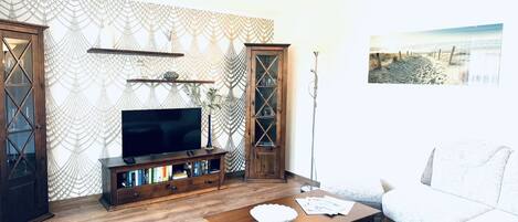 A living room with a TV, wooden cabinets, a coffee table, and a sofa.