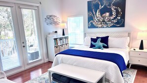 A bedroom with a bed, bedside tables, a bookshelf, a window, and a door. - 4BR Waterfront Retreat - Private Dock, Kayaks, Hot Tub & Tiki Bar  Walk to Beach (Cocoa Beach)