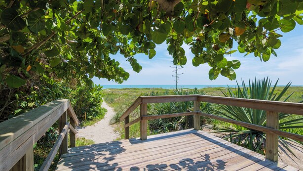 A wooden boardwalk leading to a beach with a clear view of the ocean. - 4BR Waterfront Retreat - Private Dock, Kayaks, Hot Tub & Tiki Bar  Walk to Beach (Cocoa Beach)