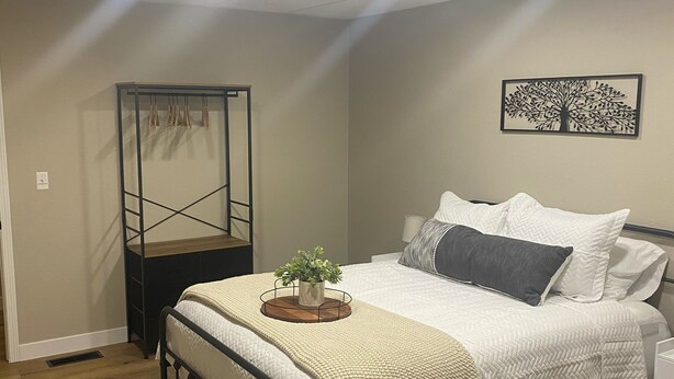 Un dormitorio con cama, mesita de noche, estante en la pared y lámpara en el techo.