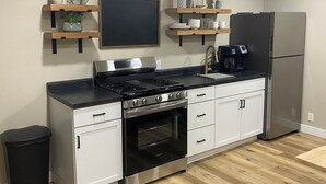 Una cocina moderna con armarios blancos, estufa de acero inoxidable y refrigerador.