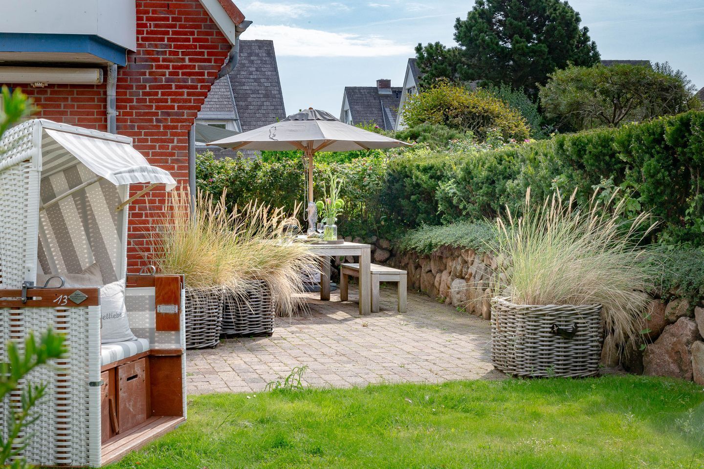 A patio with a table and chairs, surrounded by potted plants and a stone wall.