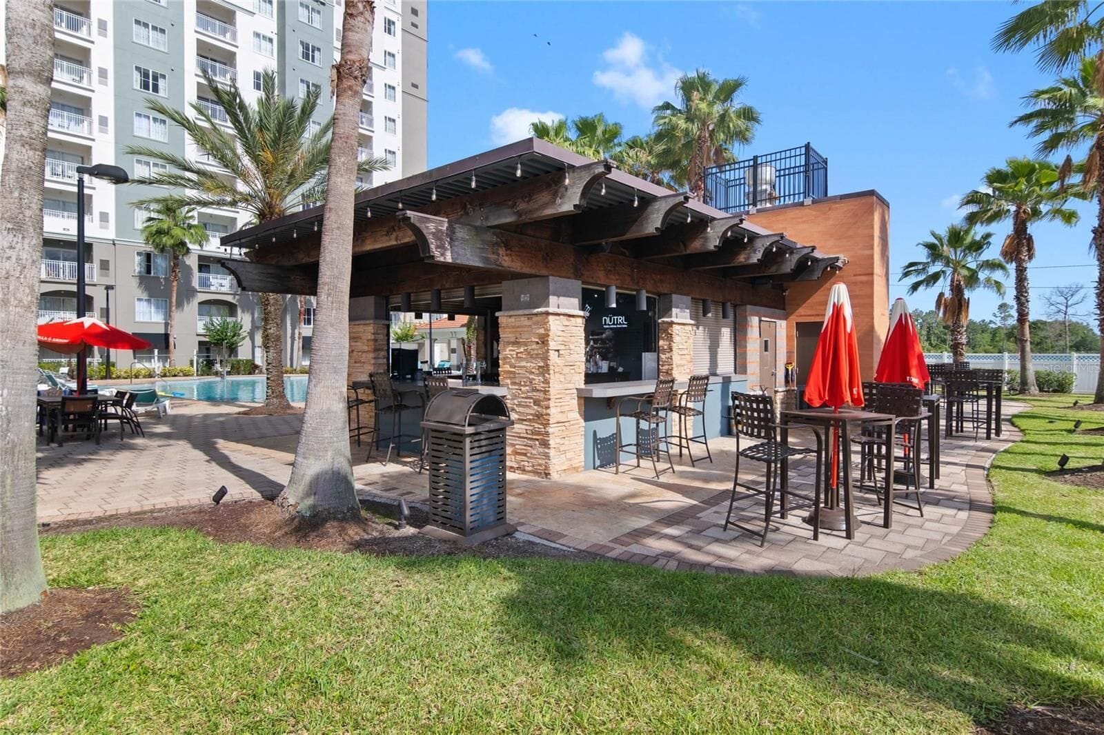 Un patio al aire libre con estación de barbacoa, asientos y sombrillas.
