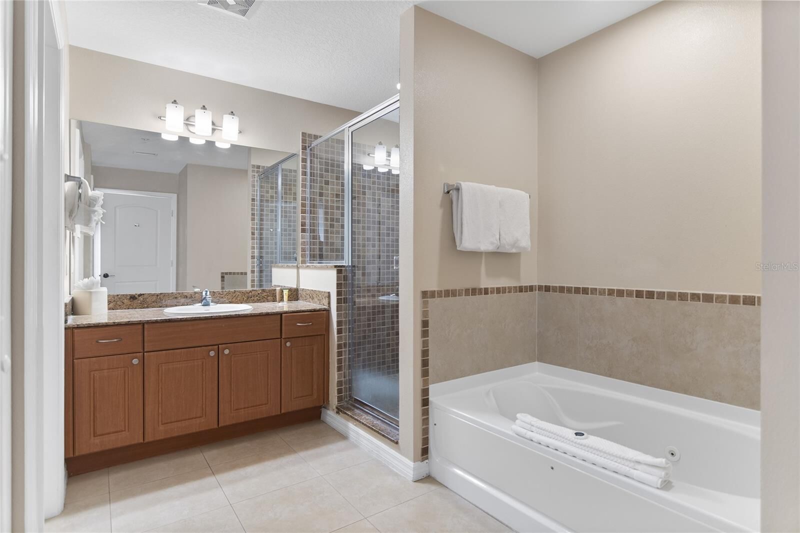 A bathroom with a bathtub, a shower, and a vanity with a mirror.